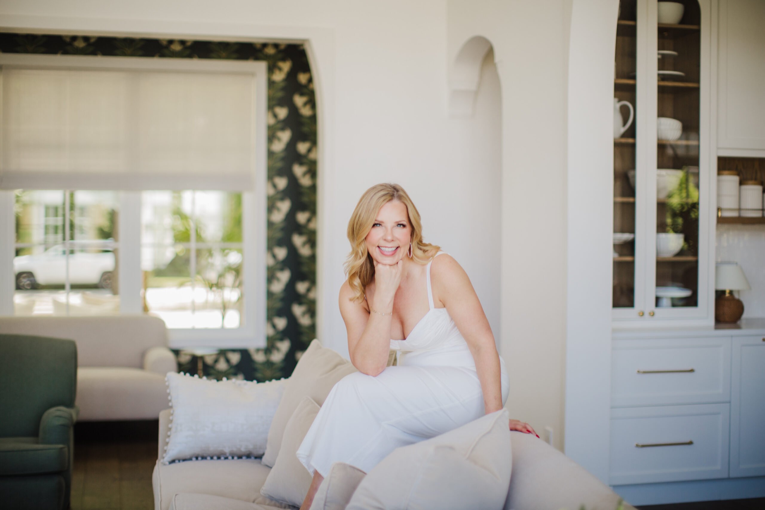 woman in a white dress on a neutral couch in a designer home